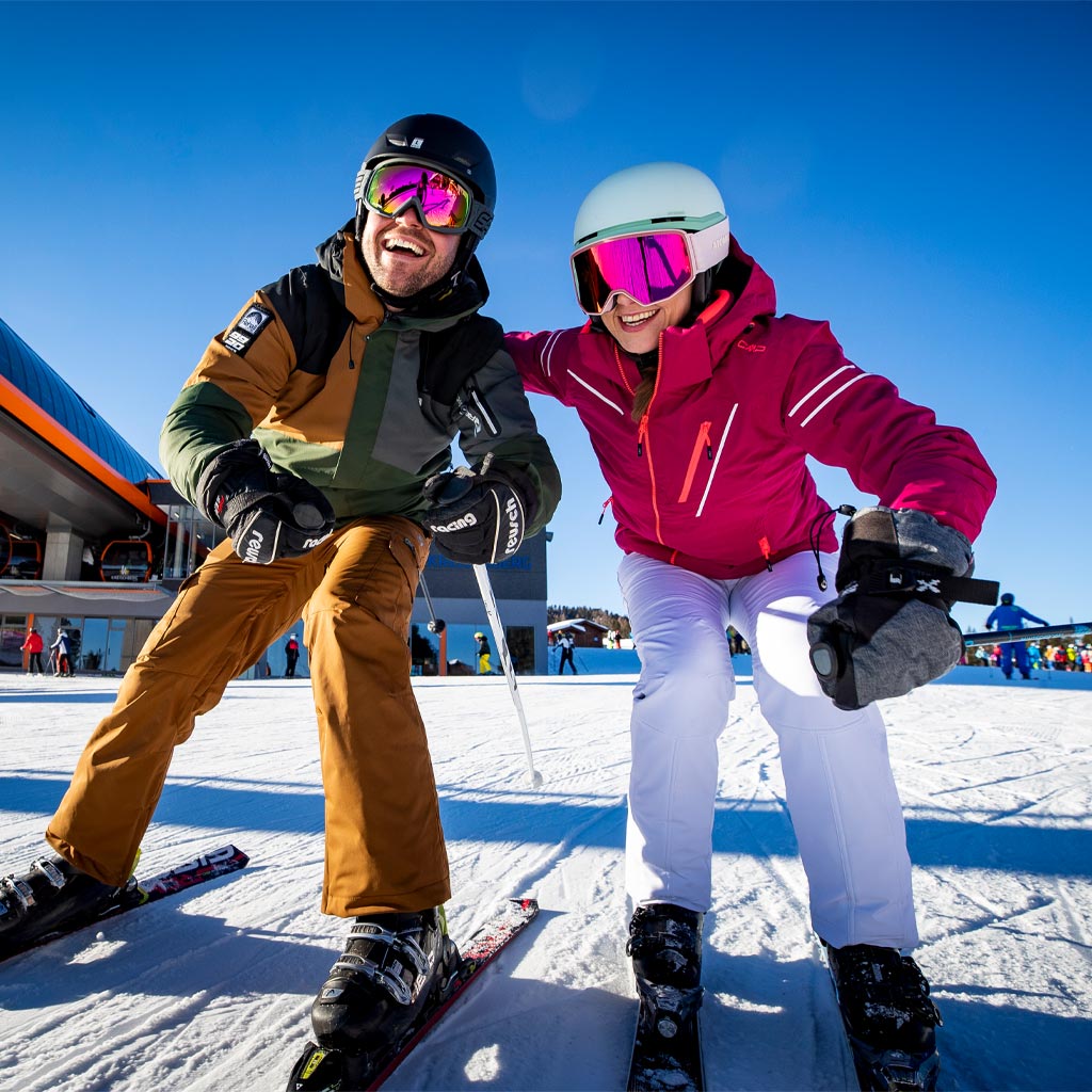 Glückliches Paar in kompletter Skiausrüstung, bereit für die Abfahrt.